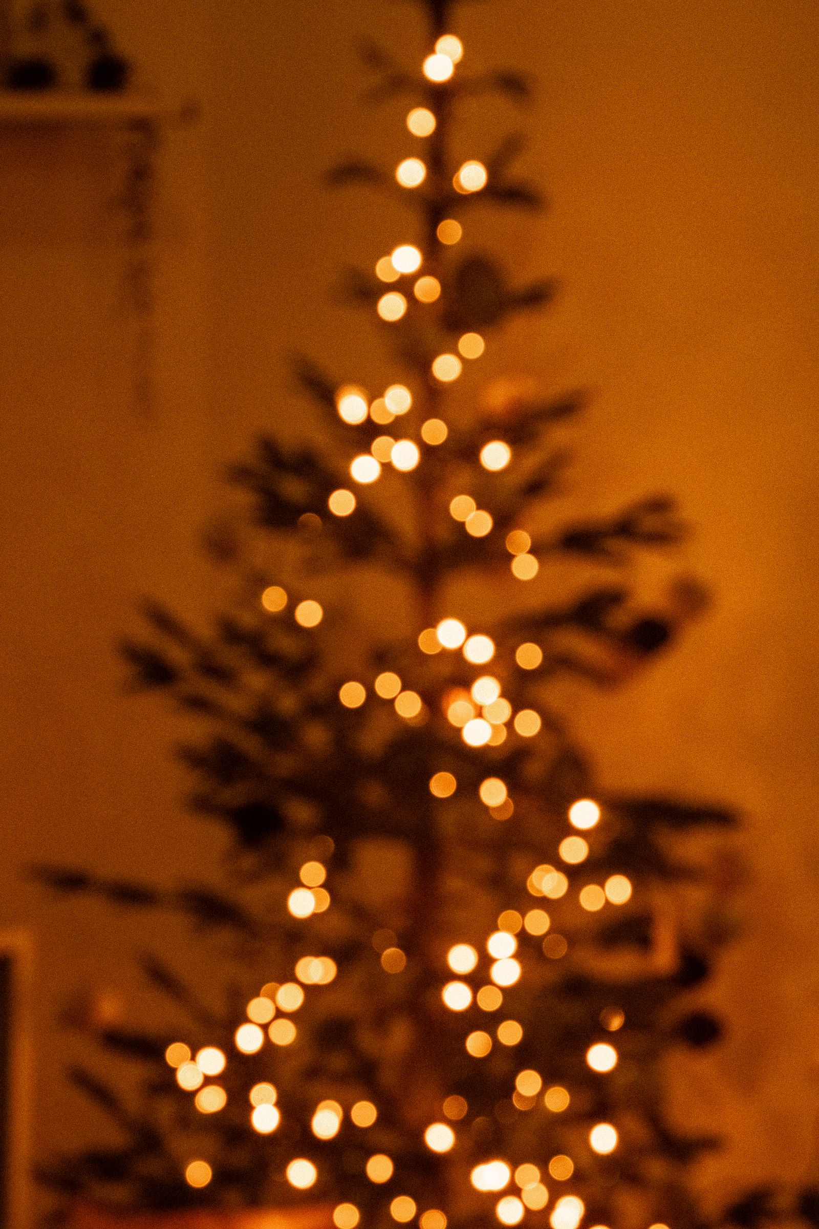 Árvore de Natal com luzes douradas desfocadas em um ambiente aconchegante